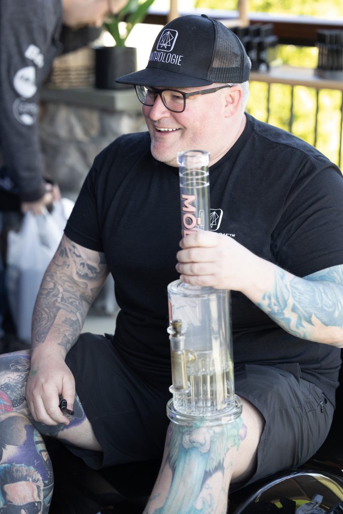 man with tattoos holding glass bong