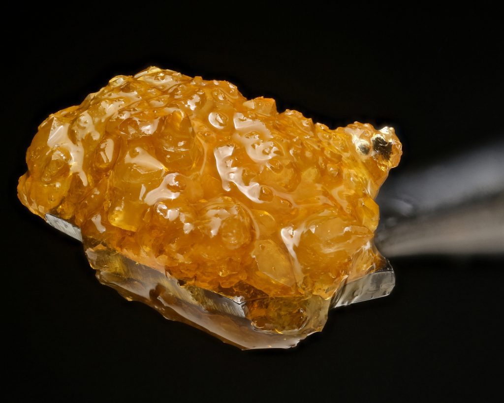 Cannabis concentrate sugar wax close up on dabbing tool on black background